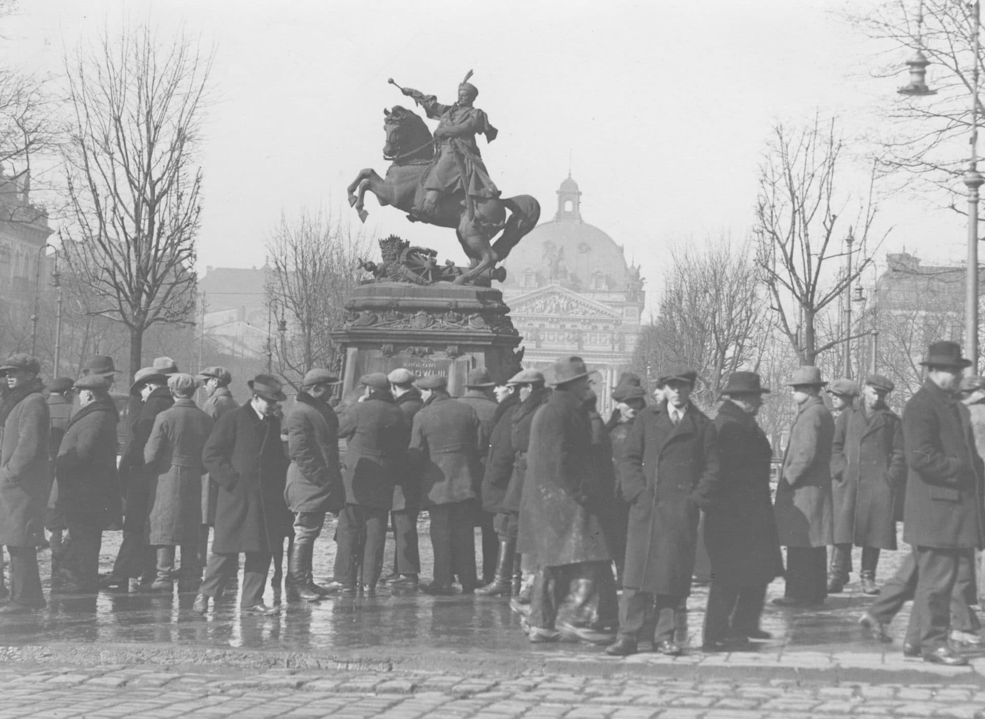 Grupa bezrobotnych mężczyzn na "giełdzie pracy" pod pomnikiem Jana Sobieskiego we Lwowie. Źródło: Narodowe Archiwum Cyfrowe.